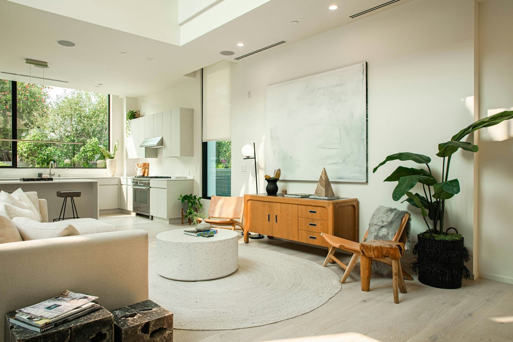 A bright open living space with plants, a wooden sideboard and a kitchen beyond
